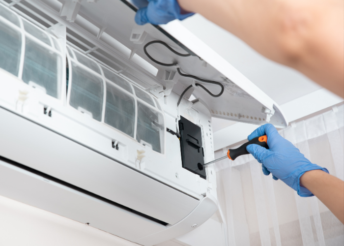 Technician in gloves repairing the internal components of a split-unit air conditioner